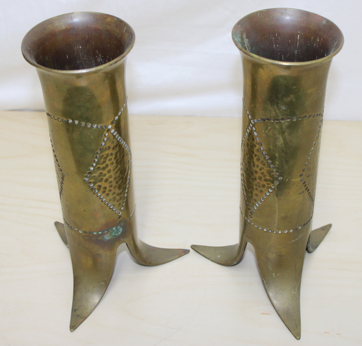 Pair of decorated brass flared top shell cases with tripod legs