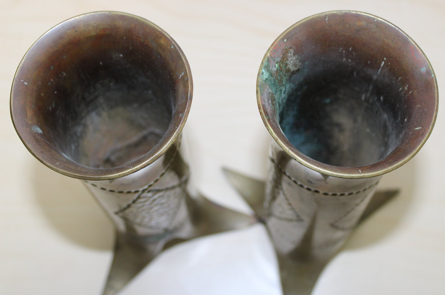 Pair of decorated brass flared top shell cases with tripod legs